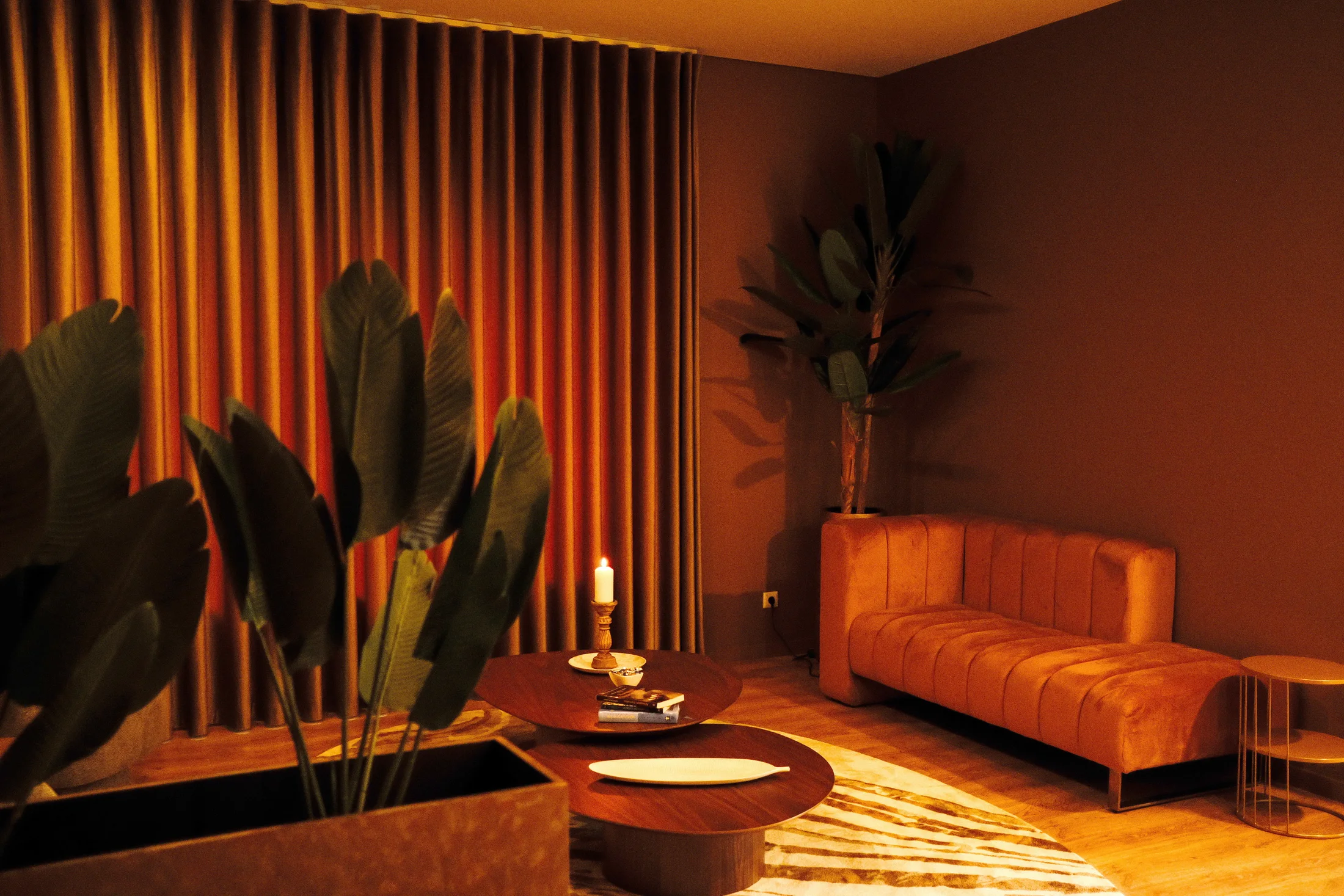 Sala Manu Hari iluminada por luz quente entre cortinas e plantas